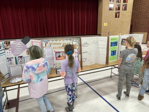 Students are looking at science projects in the gym.